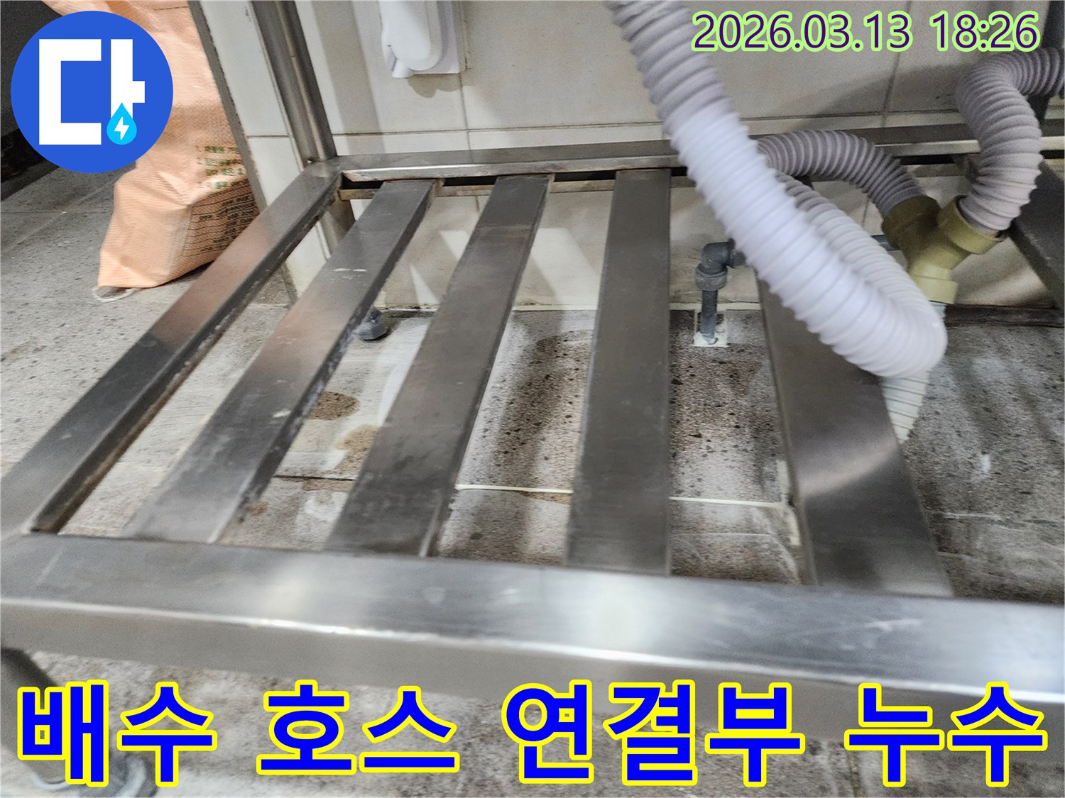 누수-현장에서-배수 호스와-연결된 배관의-손상 여부를-면밀히 검토하는-엔지니어의 모습