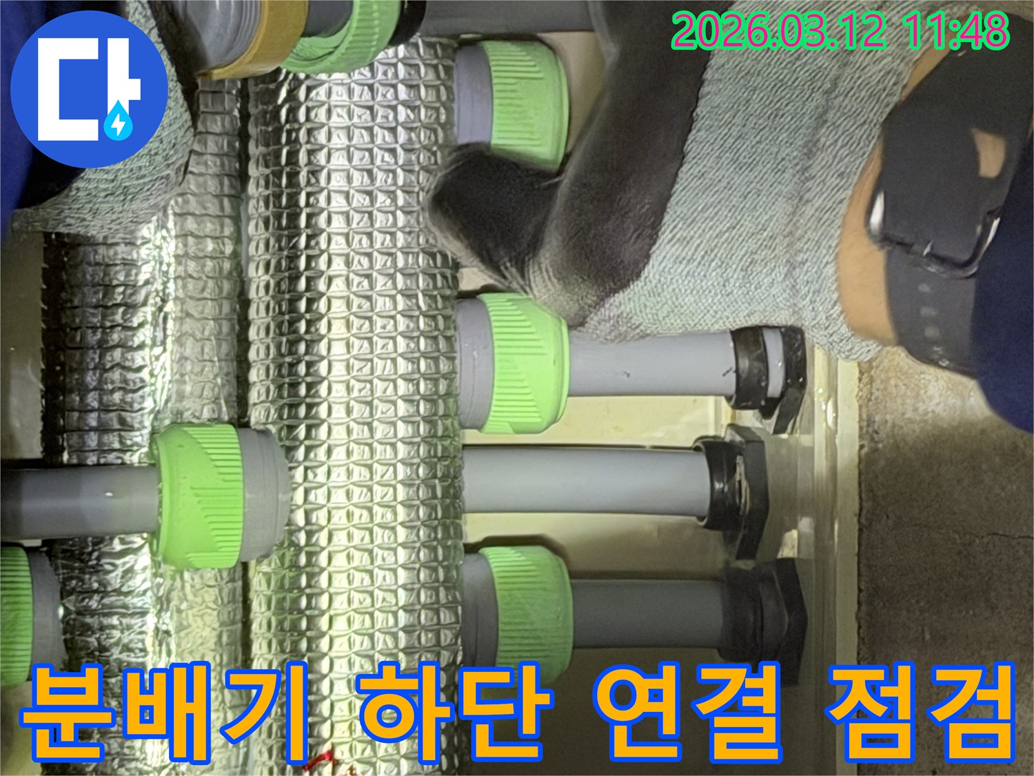 김포-지역의-전문가가-배관-분배기-하단부의-연결-지점을-세심하게-점검하며-누수-징후를-찾고-있습니다.