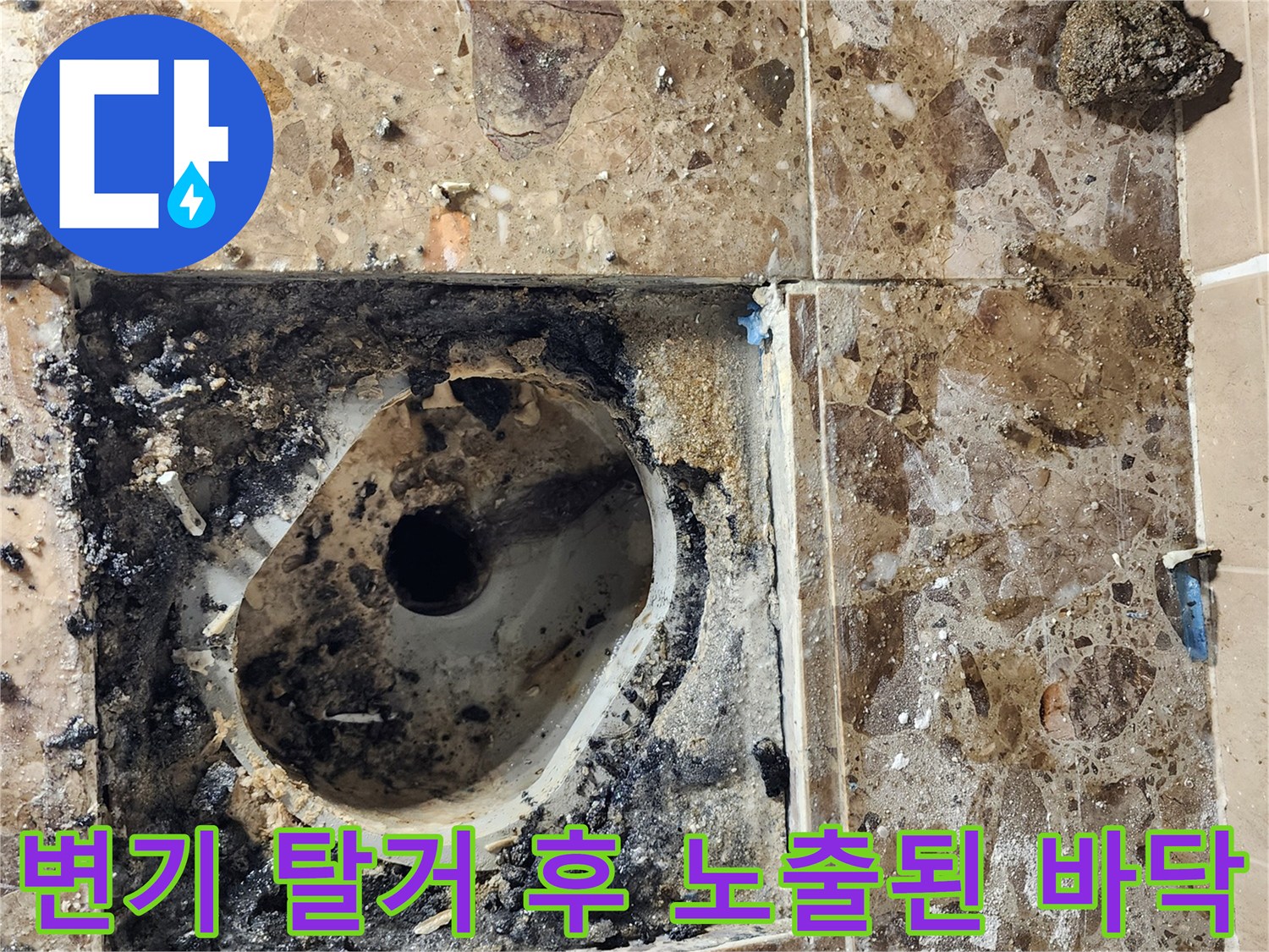 양변기 제거 후 드러난 배수구 주변의 젖은 타일면