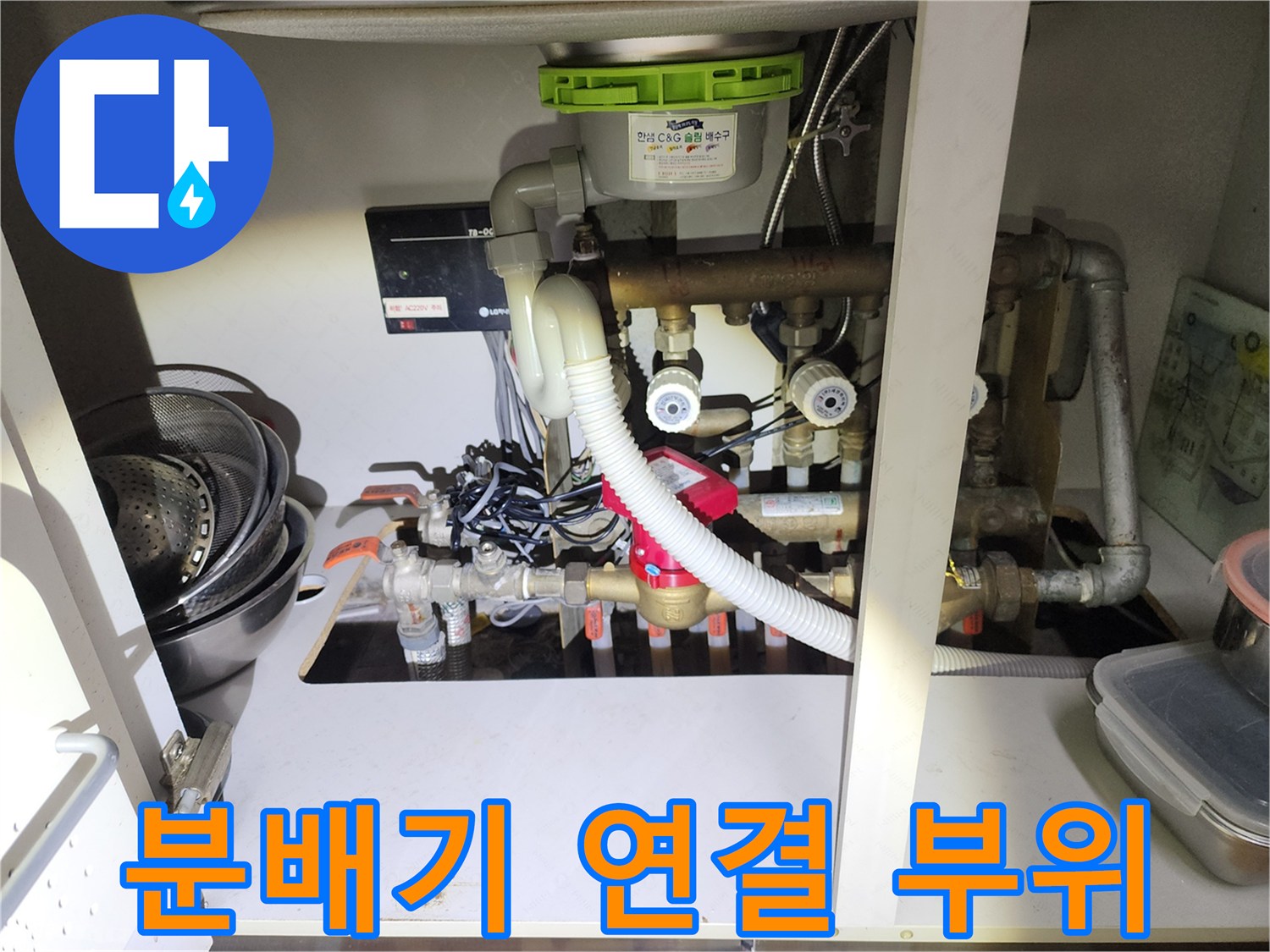 싱크대 밑 공간에 설치된 난방 분배기와 배관들