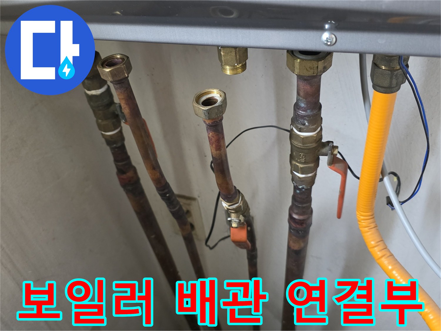 보일러실 하단에 연결된 금속 배관과 노란색 호스의 모습입니다.