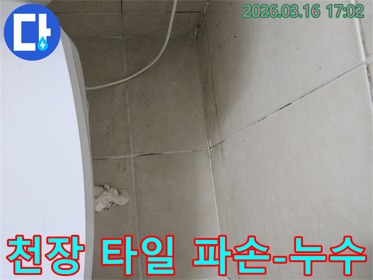 천장 타일 일부가 파손되어 내부 구조물이 노출되었으며-주변에 곰팡이와 물자국이 보이는 누수 현장입니다