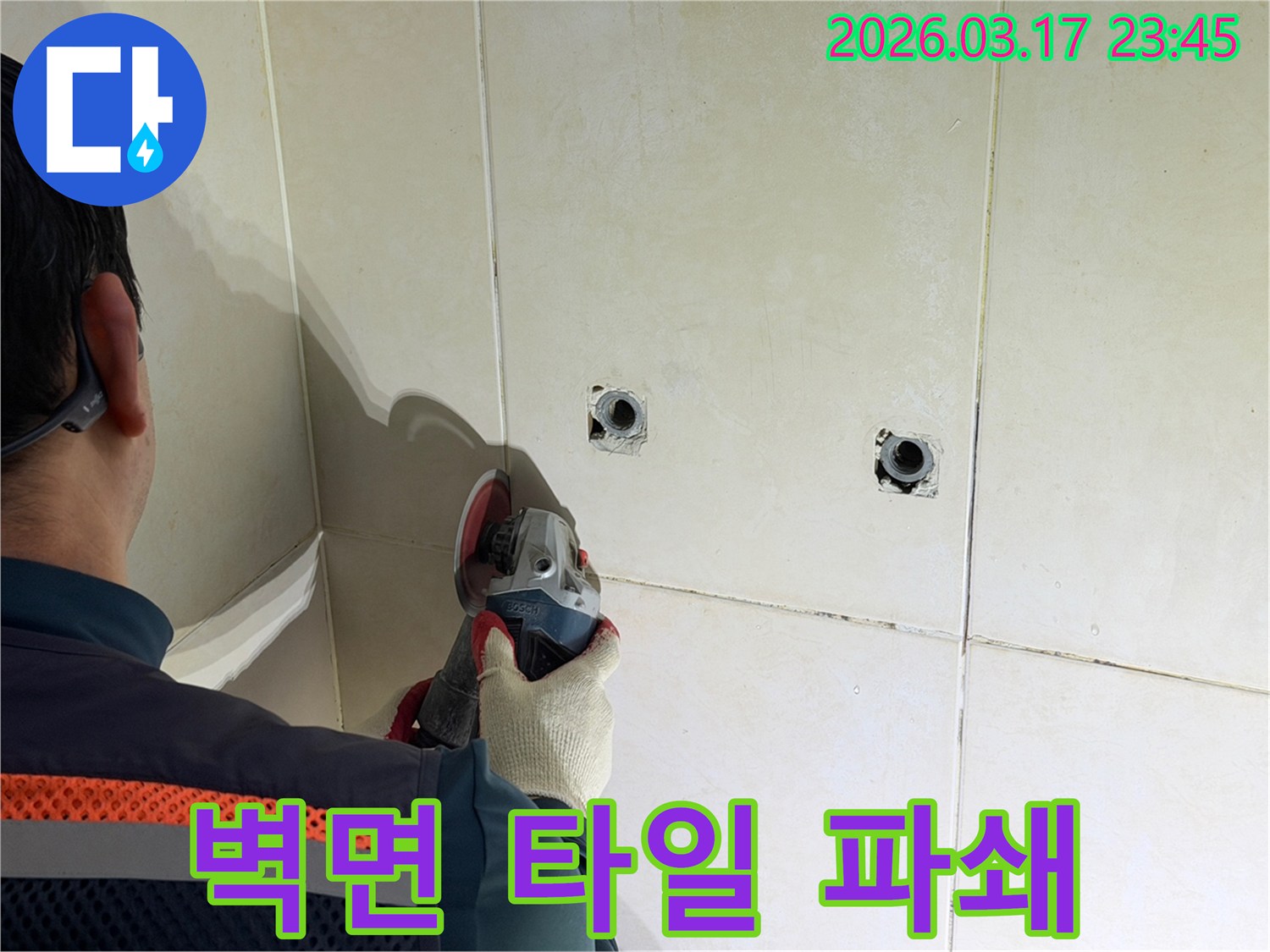 누수된 배관을-노출시키기 위해-전문가가-벽면 타일을-그라인더로-조심스럽게-파쇄하고-있습니다