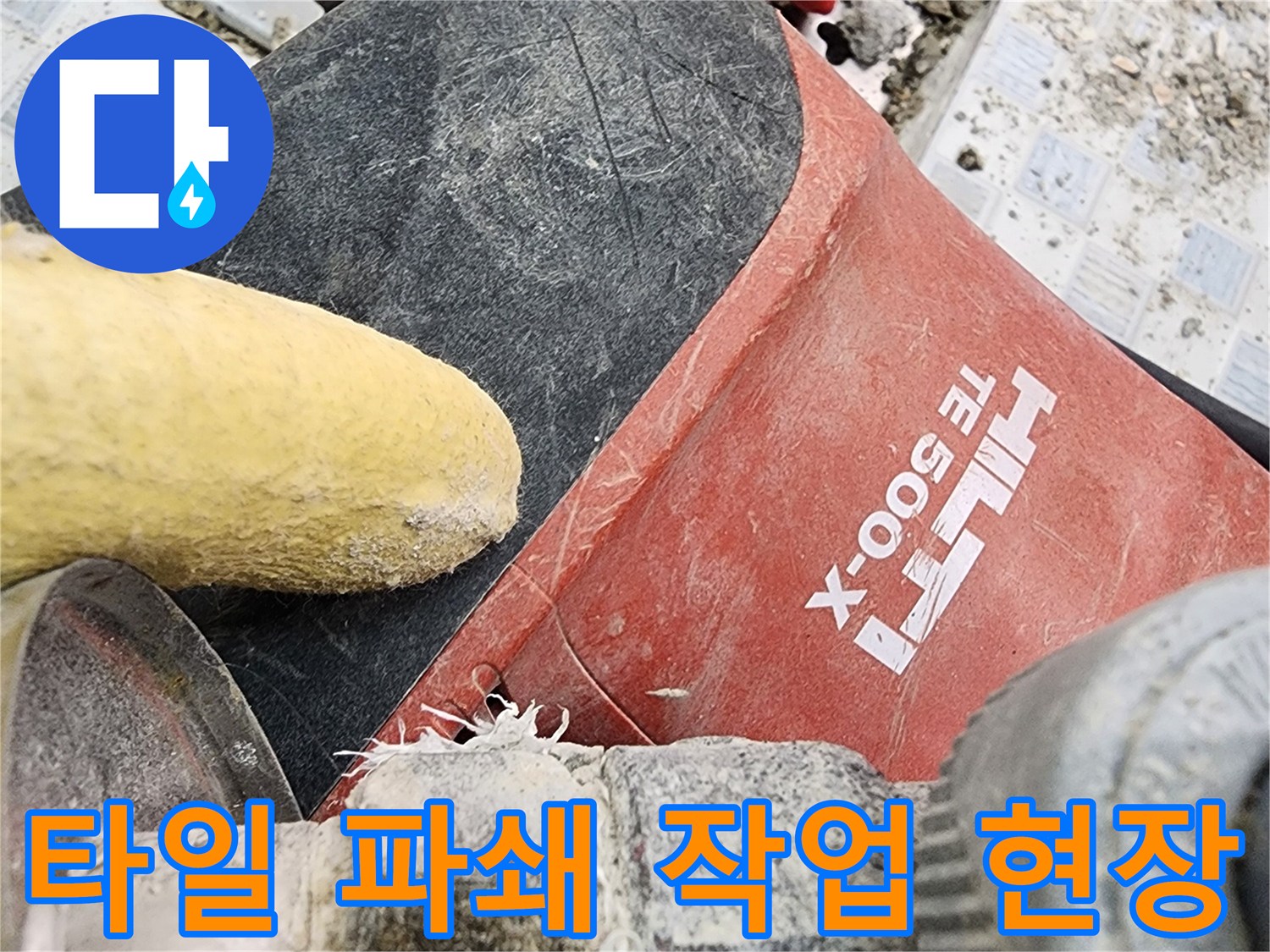 공사 중인 화장실 벽면의 깨진 타일과 붉은색 배관 부속 근처