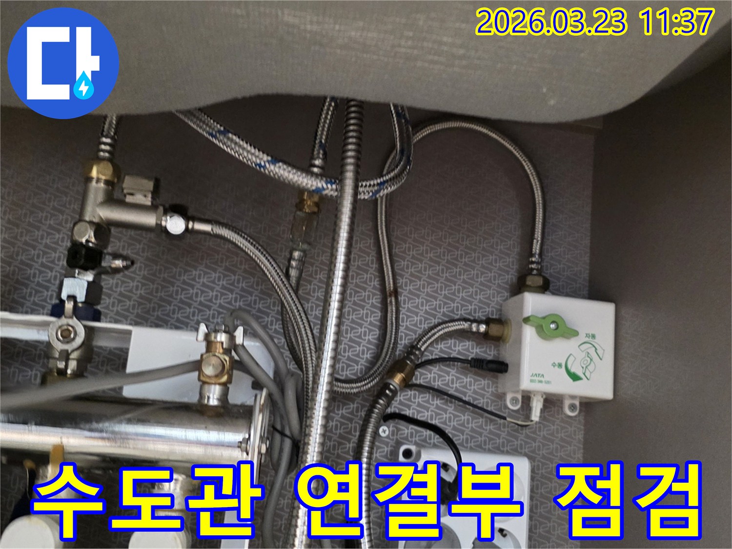 아파트 싱크대 하부의 수도관-연결부와 정수기-밸브-전기 콘센트가-복합적으로 설치된-공간을 보여줍니다.