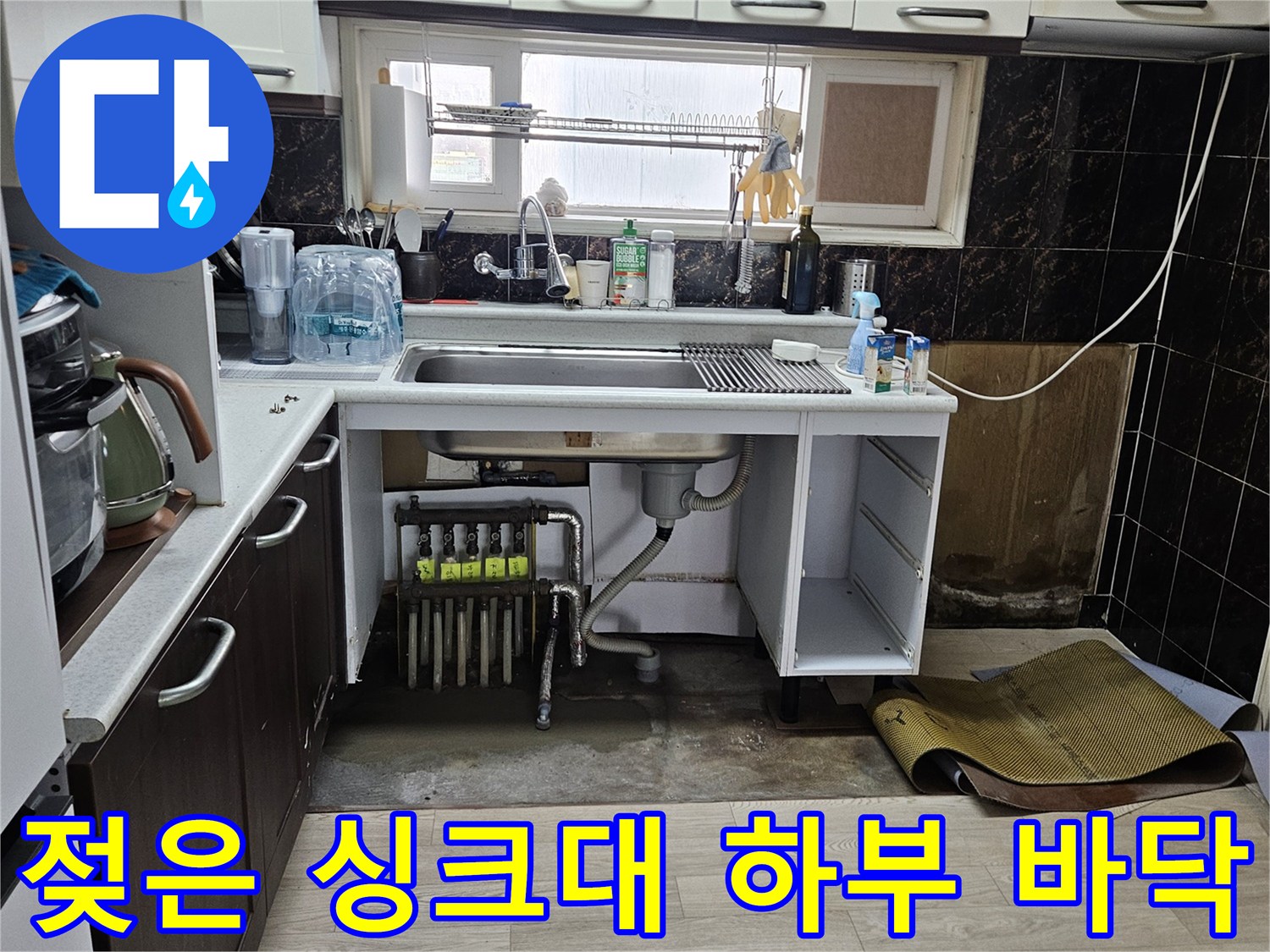 싱크대 아래 배관 주변의 물기에 젖은 바닥과 노출된 배관들