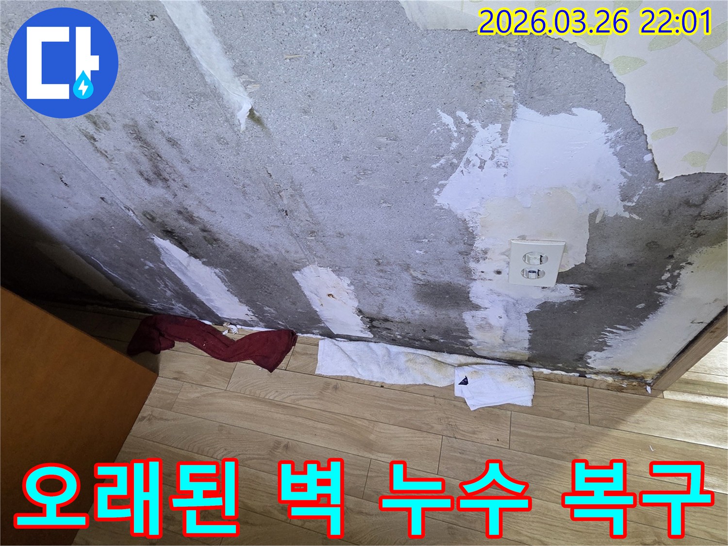 오랜-기간-누수로-인해-벽지가-벗겨지고-심한-얼룩과-곰팡이가-생긴-콘크리트-벽면-아래-물기를-흡수하는-수건이-놓인-현장