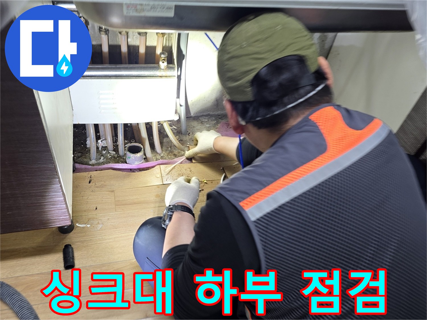 작업자가-싱크대-아래쪽-배관을-살피는-모습