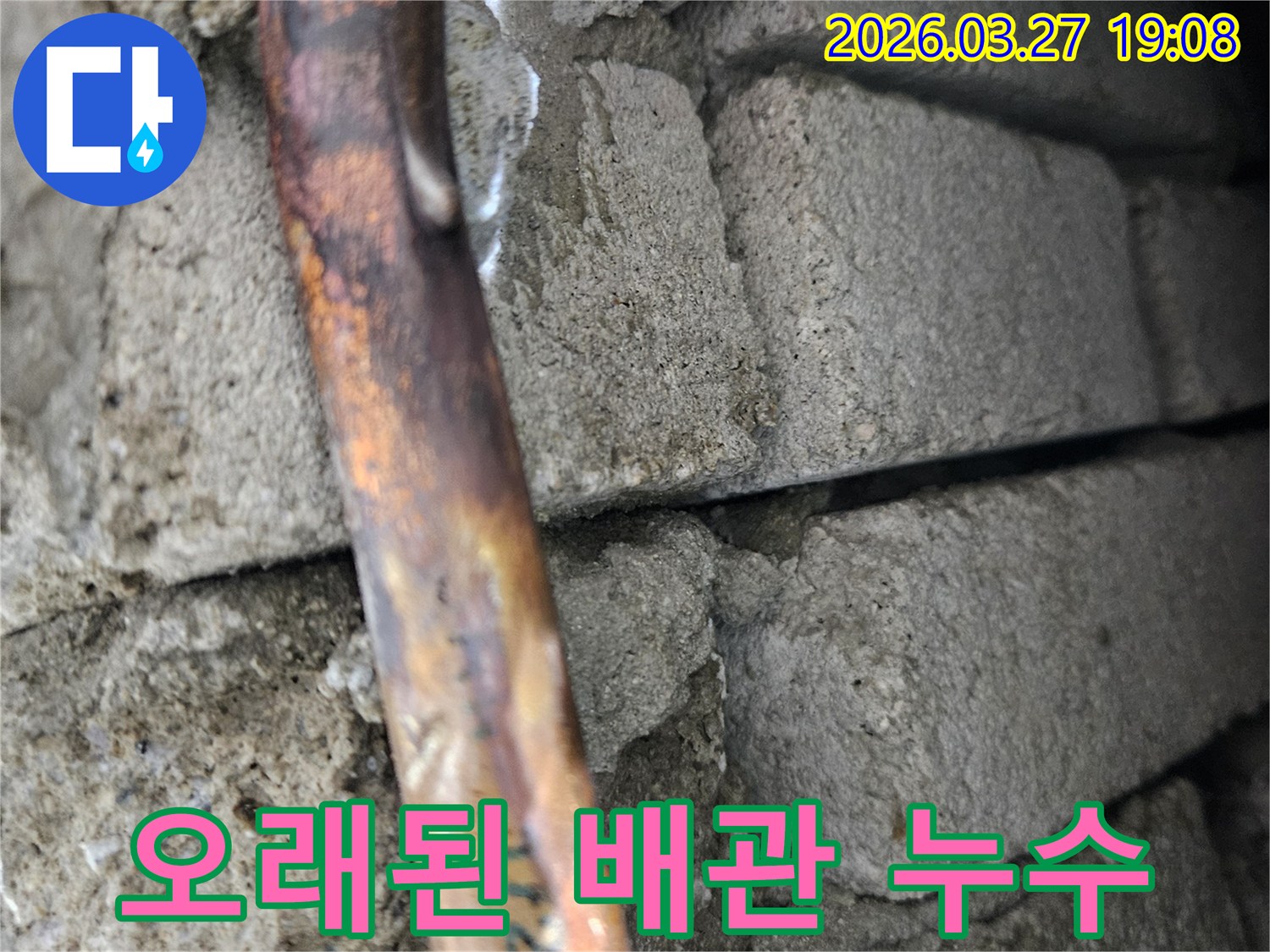 콘크리트-구조물-사이에-매설된-오래된-구리-수도-배관에서-발생한-누수-지점을-보여주는-사진