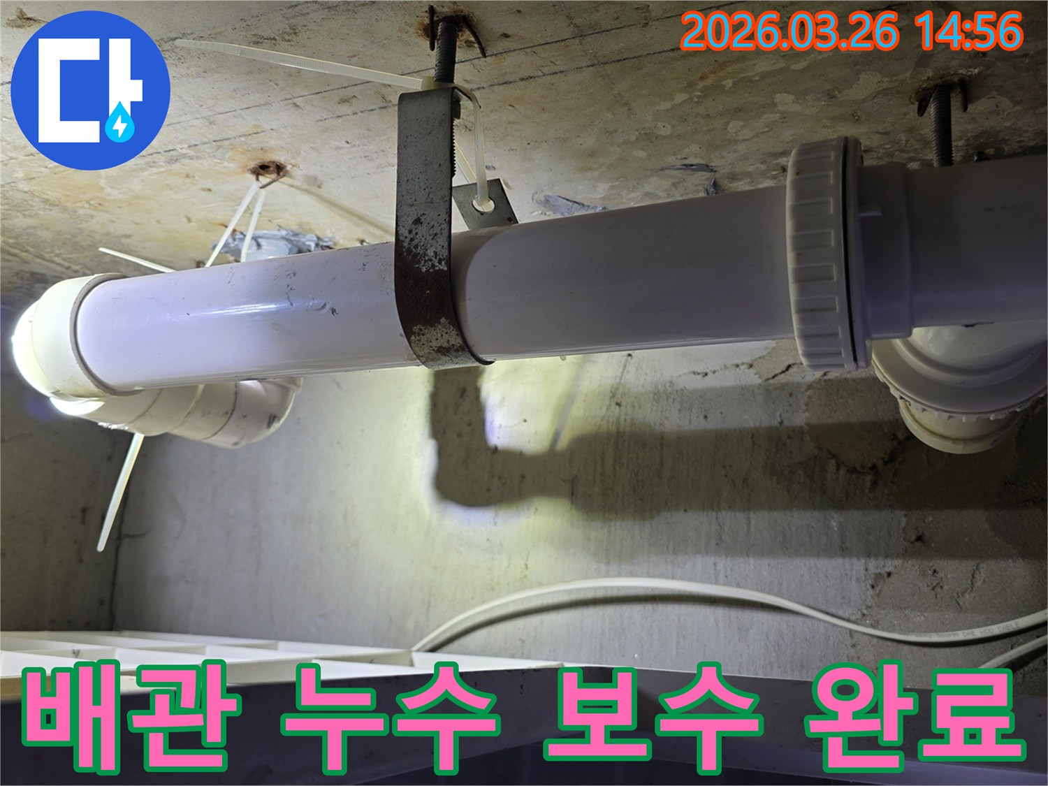 콘크리트 천장에 고정된-수리 완료된 것으로 보이는 하얀색 배관과-새롭게 보강된 금속 지지대의 모습