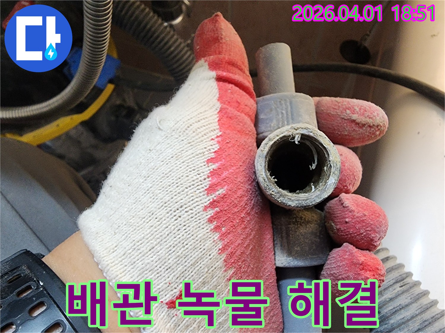 작업용 장갑을 낀 손으로-녹이 슬어 부식된 배관을 들고-녹물 문제 해결 과정을 설명하는 모습