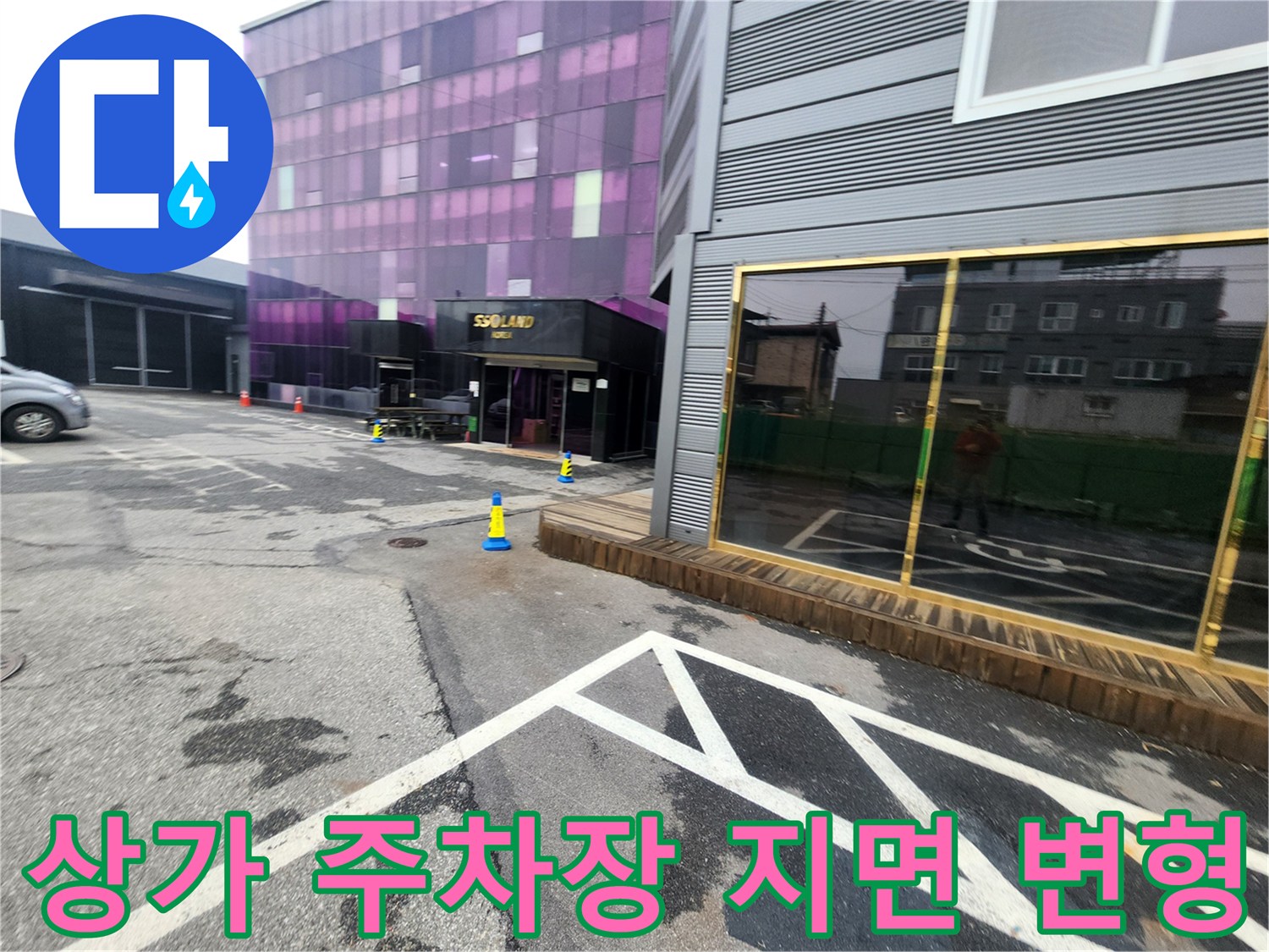 지면이 불규칙하게 내려앉은 상가 건물 앞 주차 공간