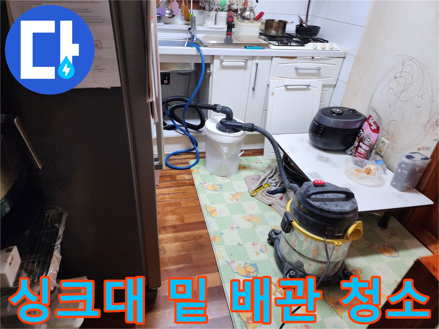 주방 싱크대 하부장에서 진행 중인 배수관 이물질 흡입 작업