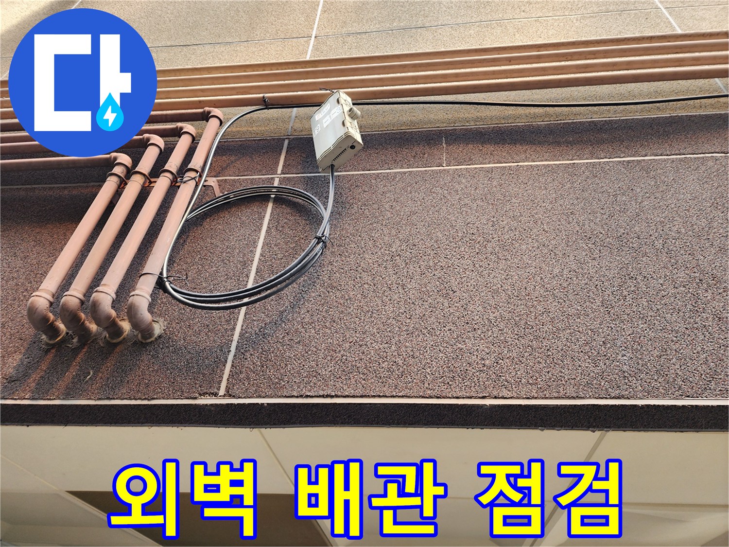 건물 외벽에 설치된 갈색 배관과 전기 배선 모습