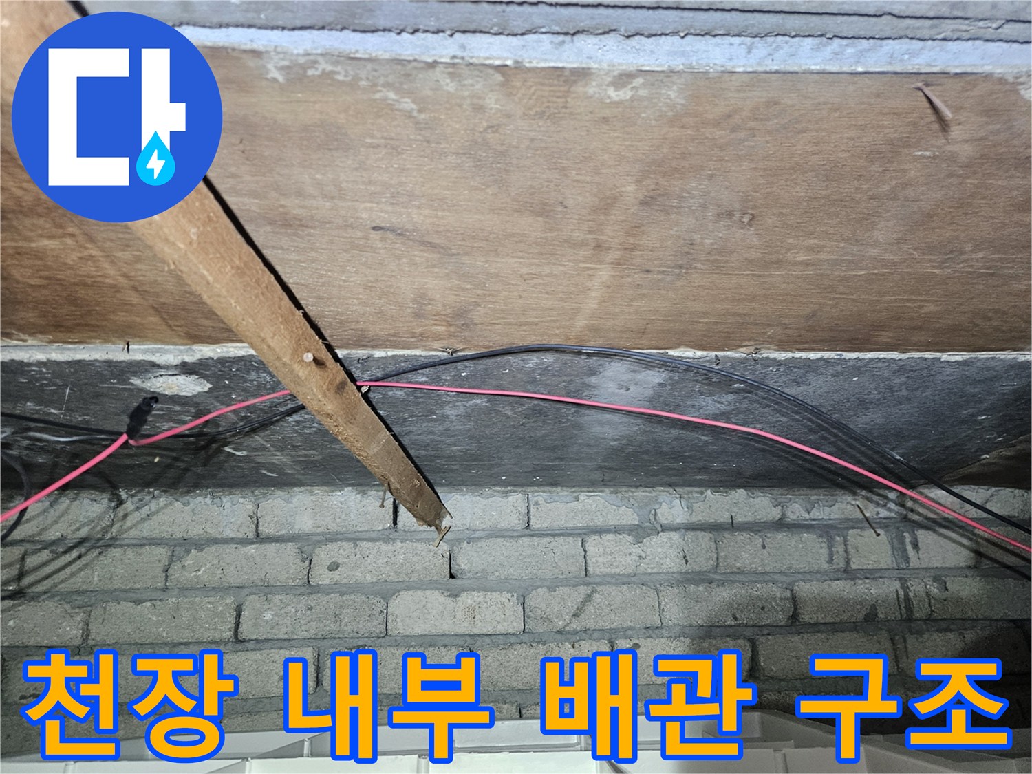 천장 목재 하부에 위치한 검은색 배관 및 전기 케이블