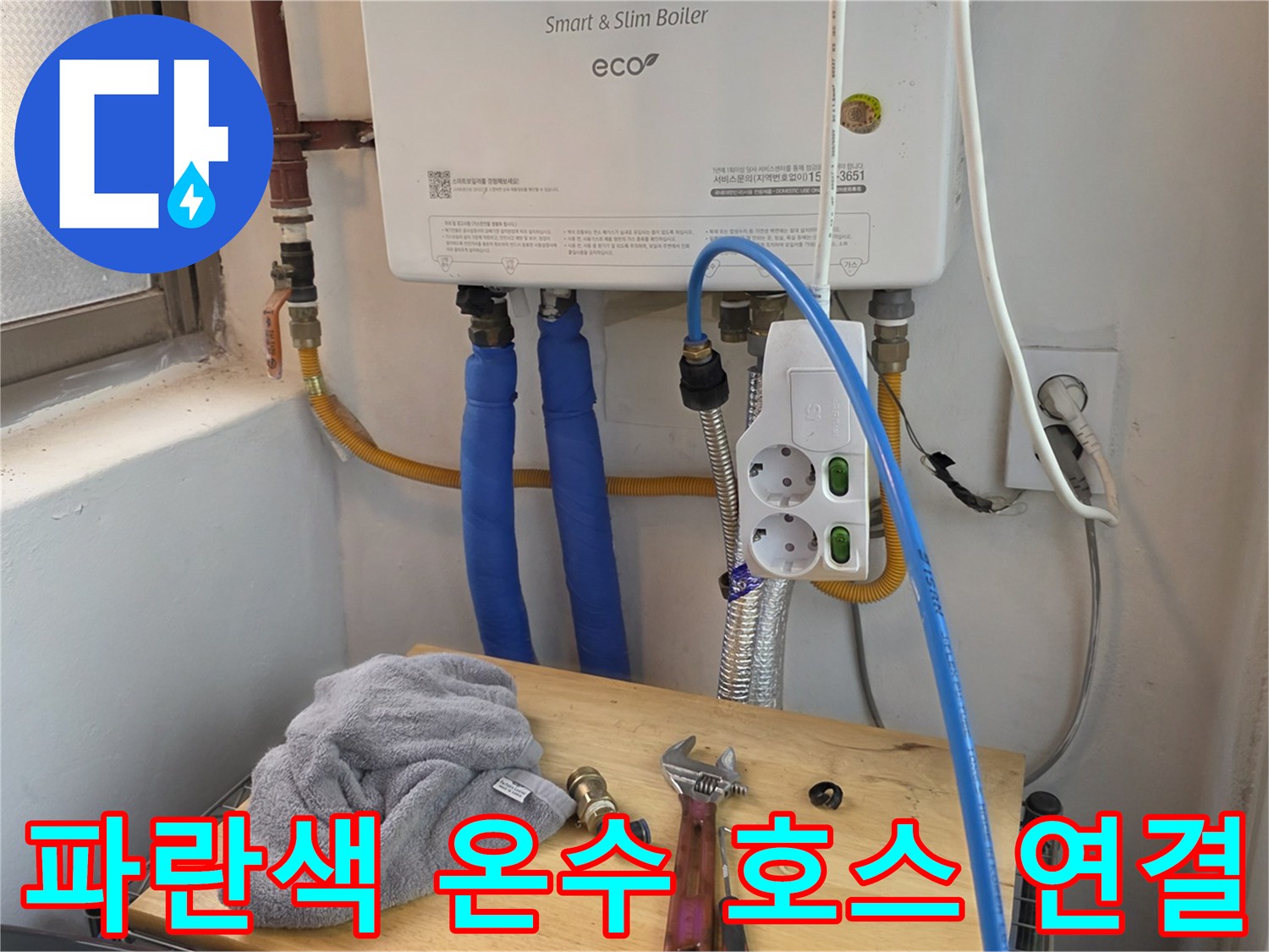 보일러 아래 설치된 파란색 급수 호스와 콘센트 전선