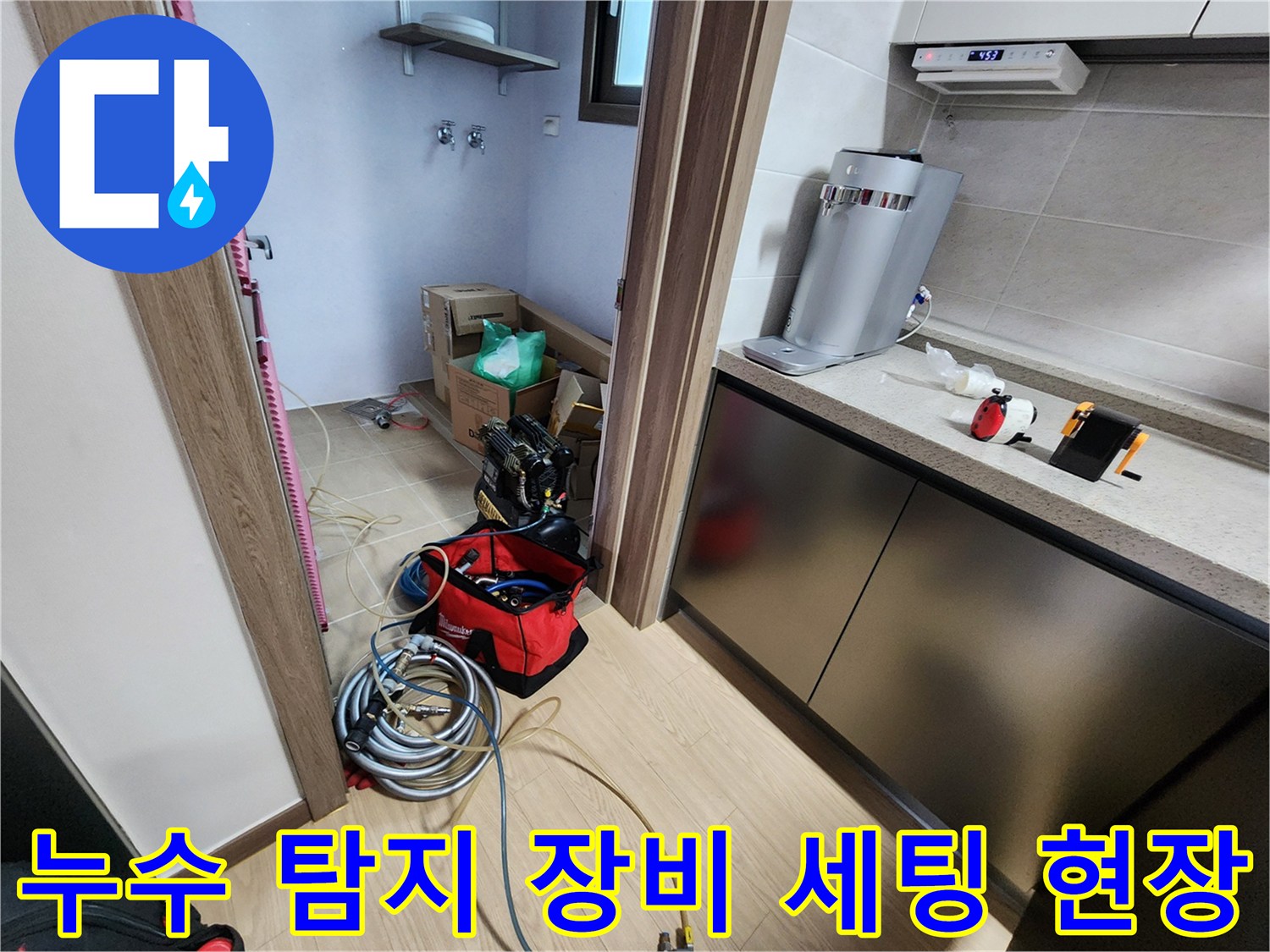 싱크대 하부 공간 작업 중 바닥에 놓인 누수 측정용 호스와 공구함
