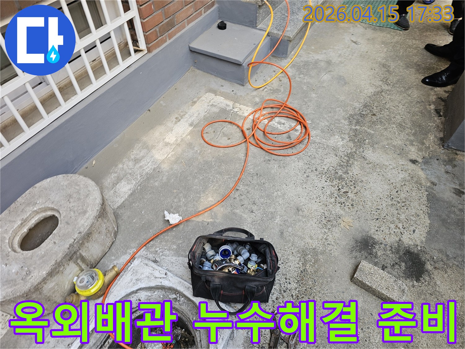 누수 전문가가-성동구 빌라의 옥외 배관 누수를-해결하기 위해-현장을 방문하여-장비를 준비하고 있습니다.