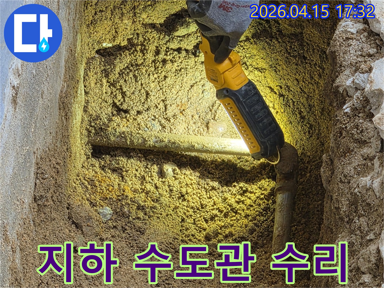전문가가-손전등으로-땅속에-묻힌-지하-수도관의-누수-지점을-확인하며-수리-작업을-준비하고-있습니다.