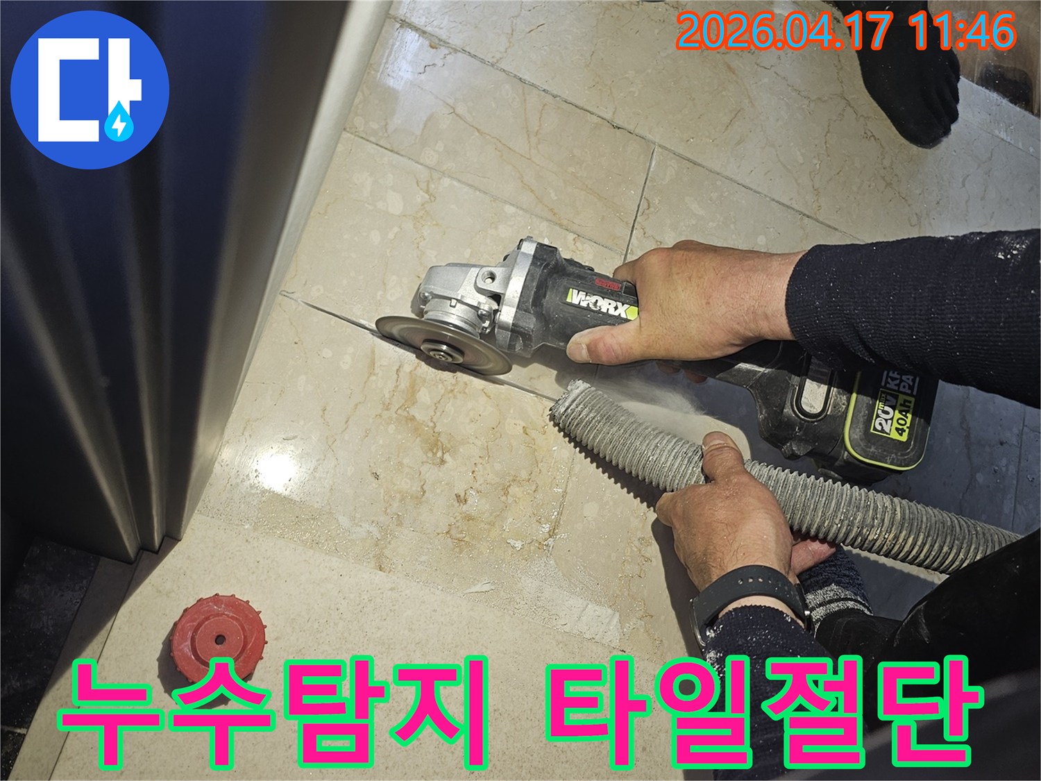 정확한 누수 지점을 찾기 위해 작업자가 그라인더로 바닥 타일을 절단하고-있으며-동시에-흡진기로-먼지를-제거하여-깨끗한-작업-환경을-유지하는-모습입니다.