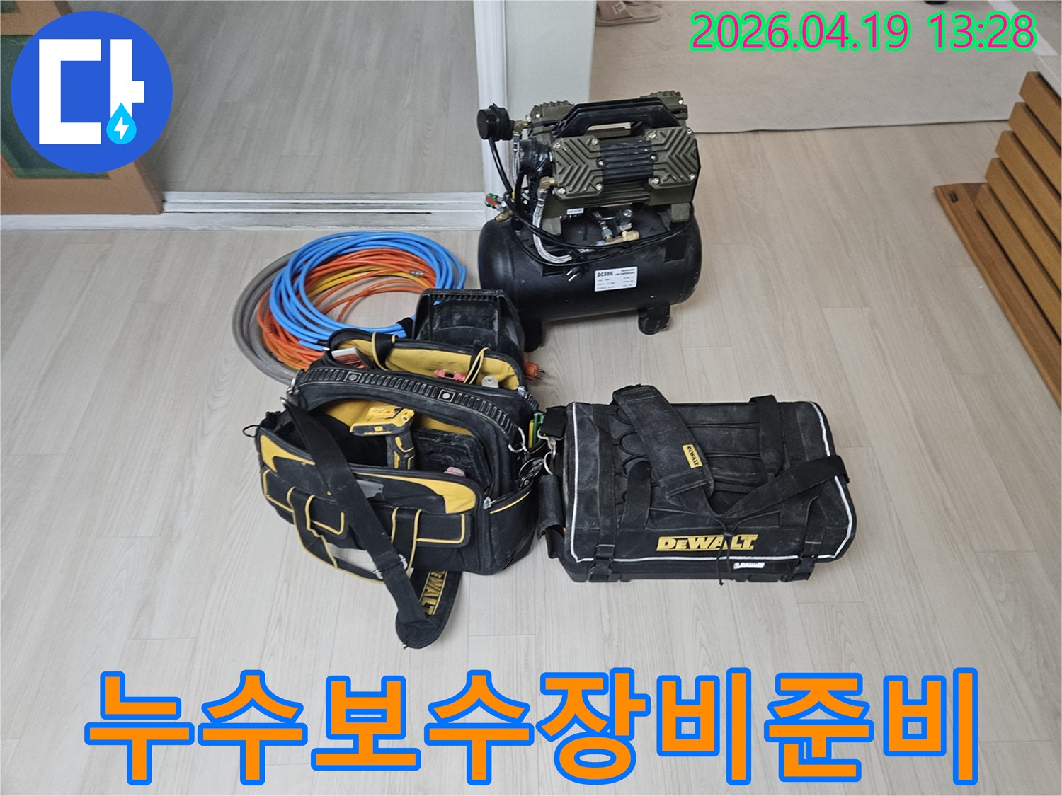 누수 보수 작업을 위한-전문 장비들이 바닥에 가지런히 놓여있습니다-에어 컴프레서와-다양한 공구 가방-그리고 튼튼한 배관 자재들이 보입니다.