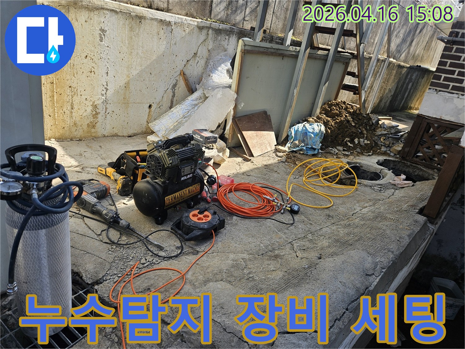 누수 현장에서-에어 콤프레셔-함마드릴-호스-전선릴 등-다양한 전문 공구들이-콘크리트 바닥 위에-작업 준비를 위해-정돈되어 있는 모습