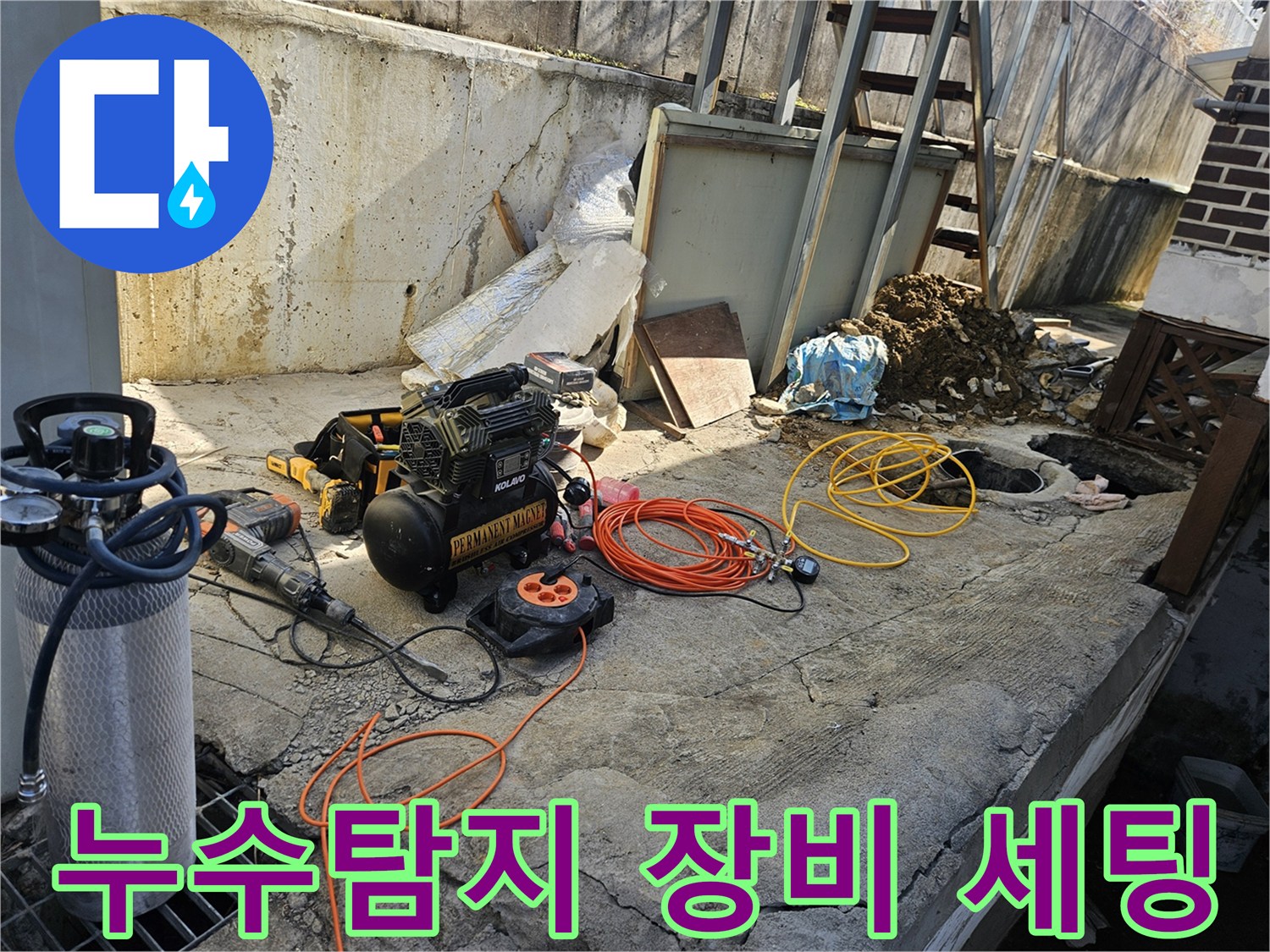누수 현장에서-에어 콤프레셔-함마드릴-호스-전선릴 등-다양한 전문 공구들이-콘크리트 바닥 위에-작업 준비를 위해-정돈되어 있는 모습