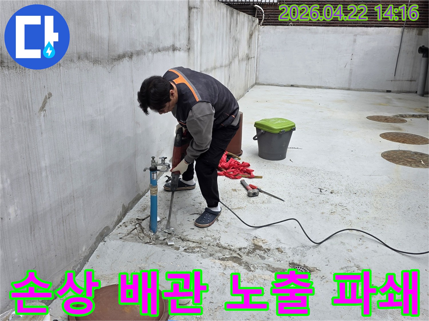 누수 엔지니어가-외부 수도관 누수 지점의 손상된 배관을 노출하기 위해-콘크리트를 파쇄하는 모습