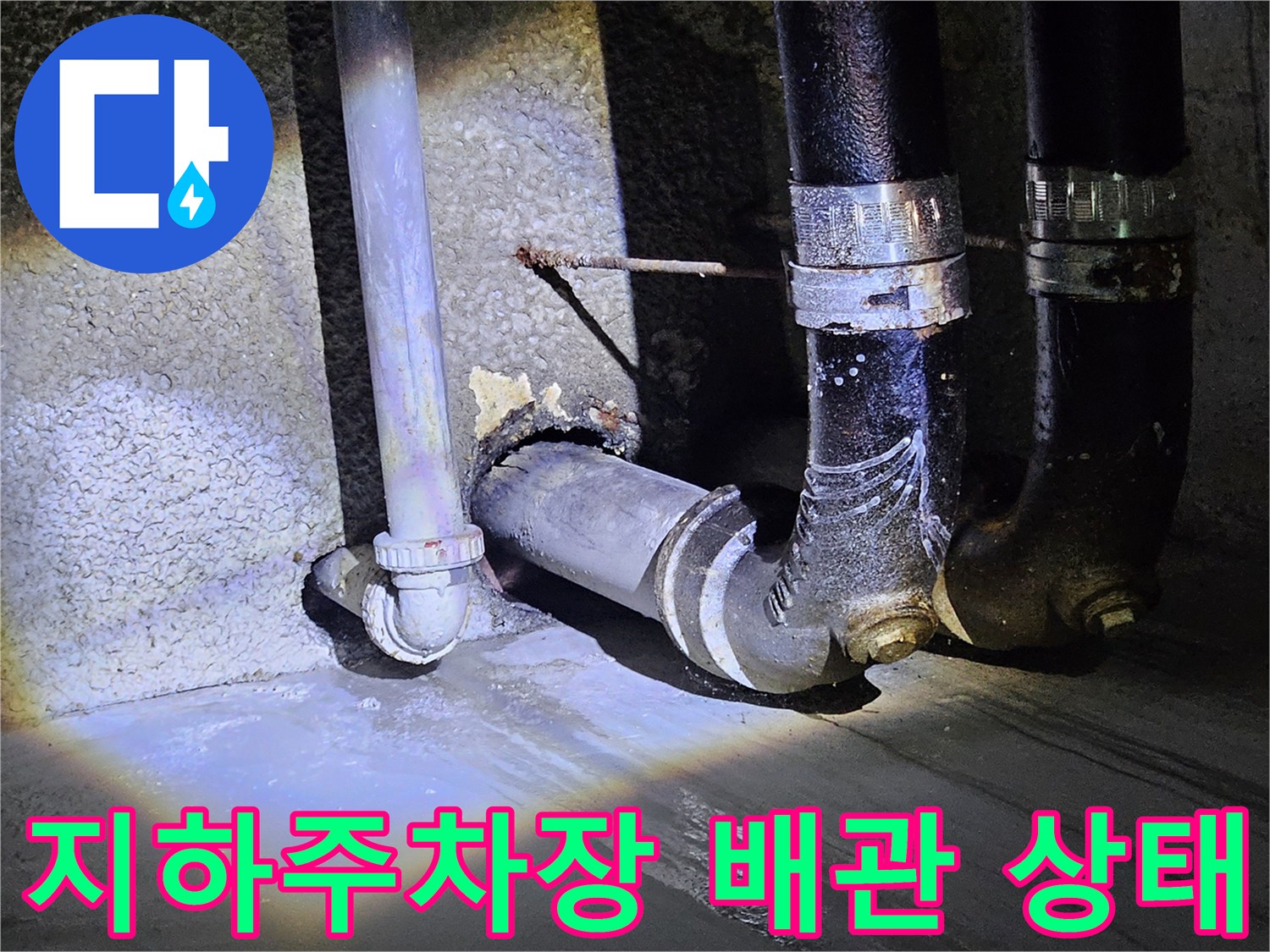 지하 주차장 벽면의 검은색 배관과 노출된 연결 부위