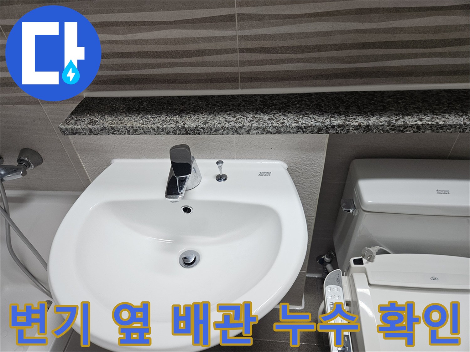 변기와-세면대-사이의-좁은-공간에-위치한-배관-연결부를-점검하는-장면입니다