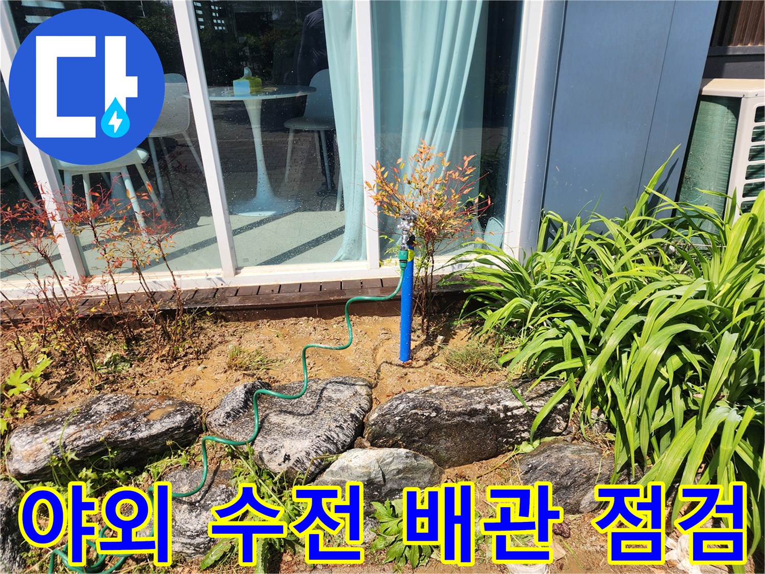 파란색 배관과 연결 부위가 노출된 실외 수전 모습입니다.