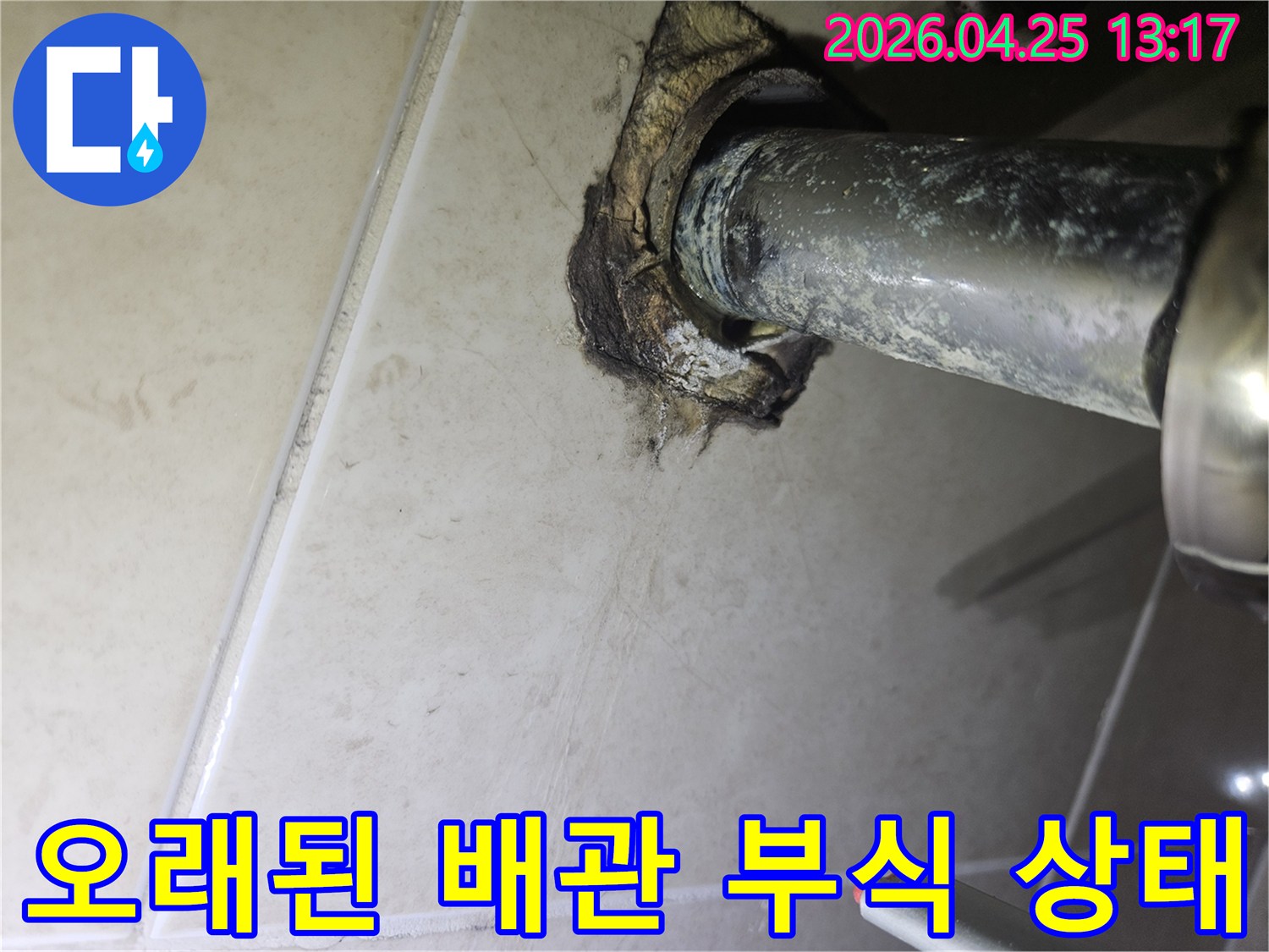 욕실 타일 벽면을 뚫고 나온-오래된 배관 주변의-심각한 부식과 누수 흔적을 보여주는 사진