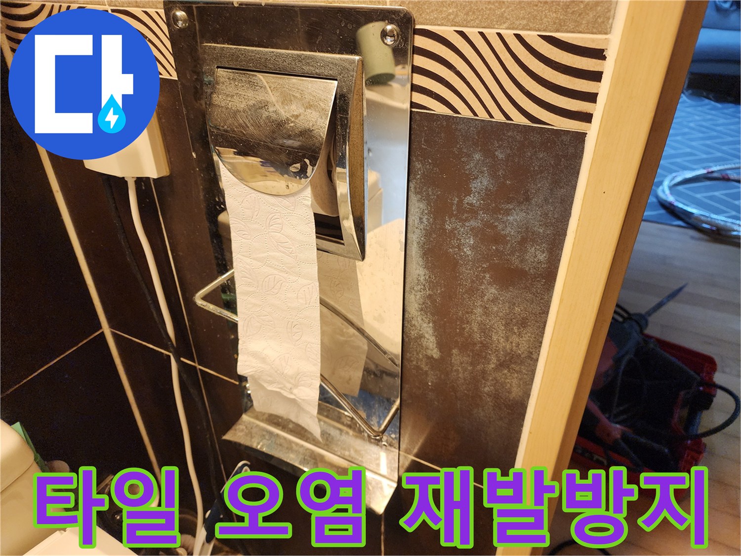 이 이미지는-욕실 타일 벽면의-오염된 부분과-휴지걸이 주변의-마감 상태를-보여주며-재발 방지-대책을-설명하기 위한-사진입니다.