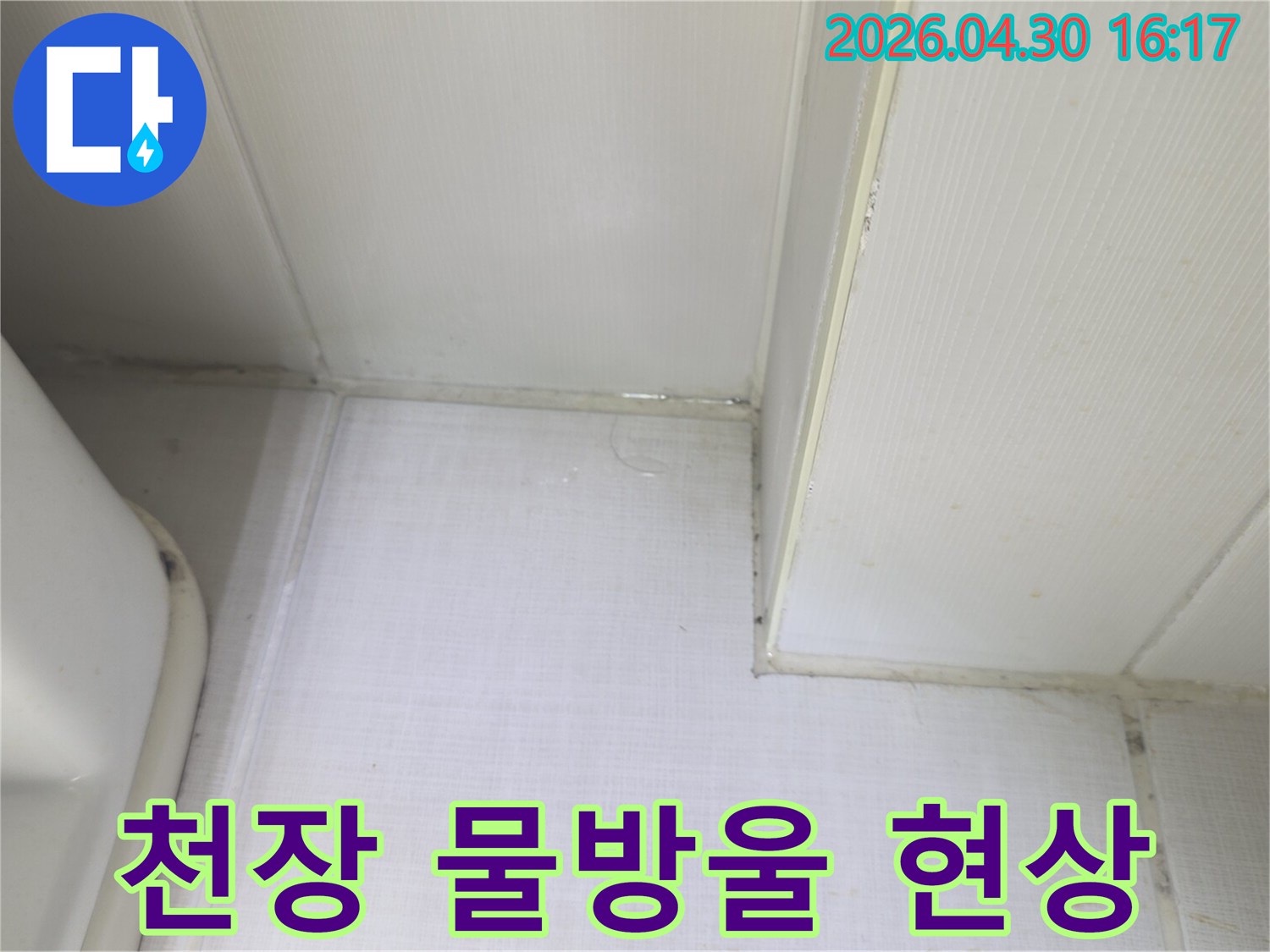 천장과 벽의 접합부에서 물방울이 맺히고-벽지가 젖어있는 상태를 보여주는-누수 발생 현장의 클로즈업 이미지