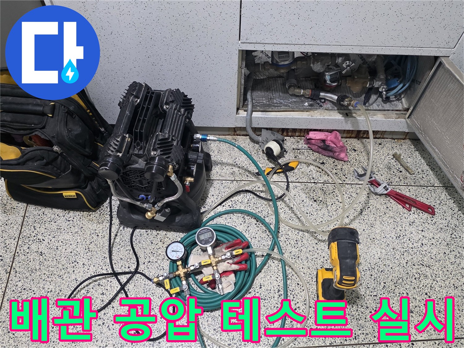 싱크대 점검구 내부 배관에 연결된 압력 측정 장비와 콤프레샤