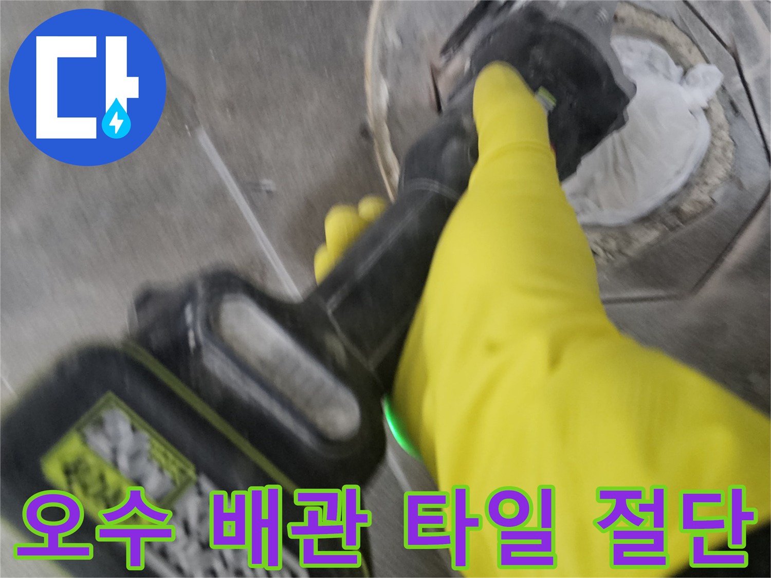 노란색 보호 장갑을 착용한-작업자가-전동 공구를 이용해-오수 배관 주변의-굳은 타일을-조심스럽게 절단하는 모습입니다.