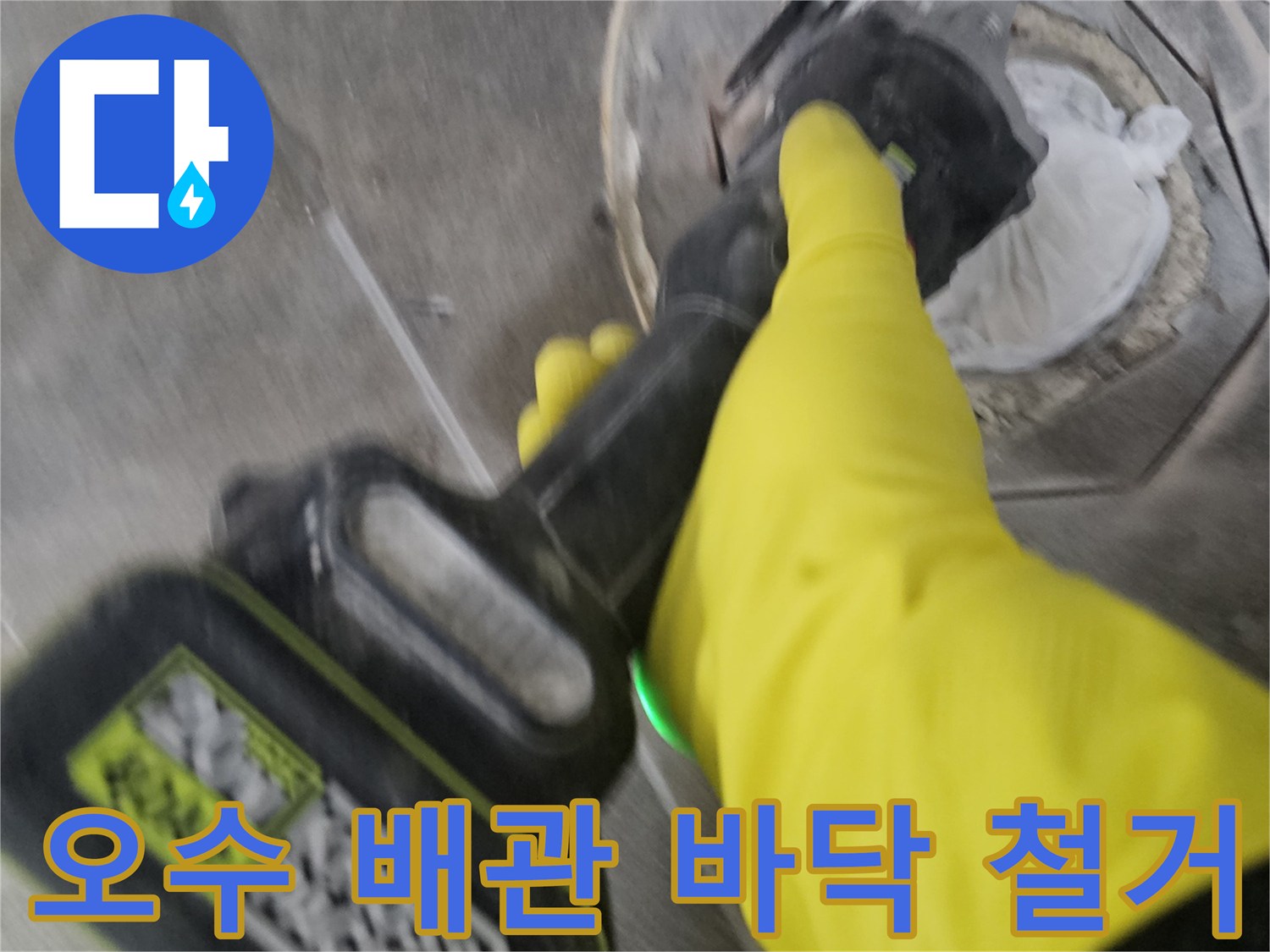 노란색 보호 장갑을 착용한-작업자가-전동 공구를 이용해-오수 배관 주변의-굳은 타일을-조심스럽게 철거하는 모습입니다.