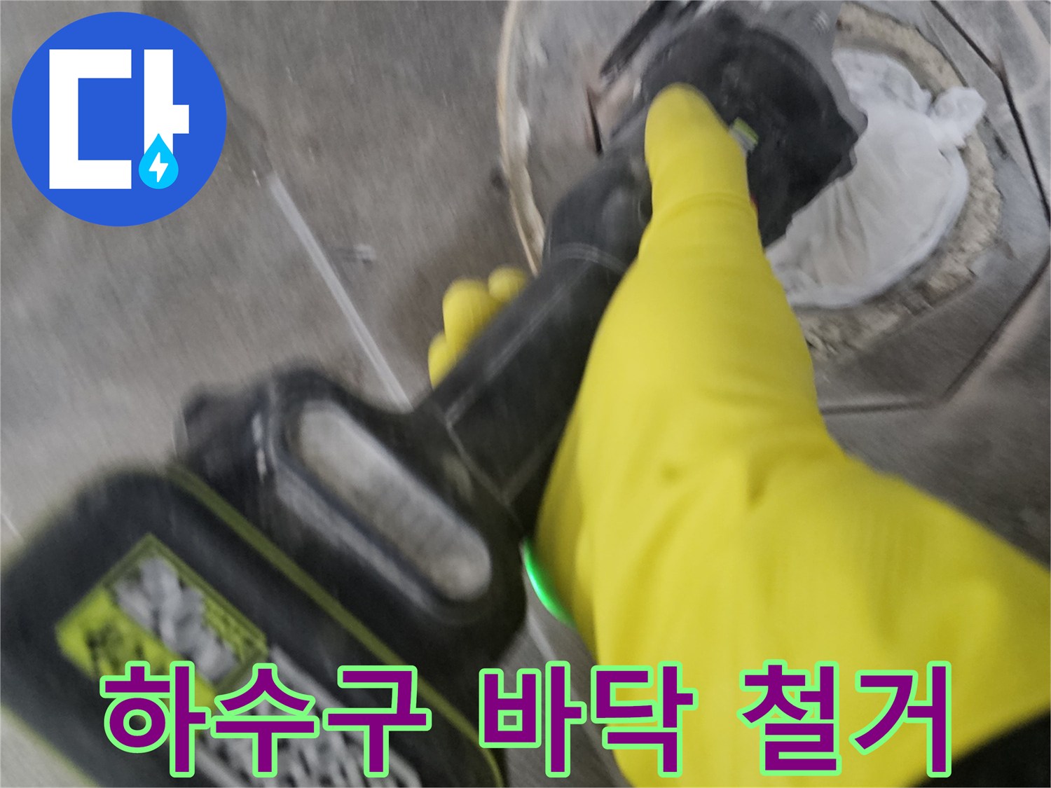 노란색 보호 장갑을 착용한-작업자가-전동 공구를 이용해-하수구 주변의-굳은 타일을-조심스럽게 철거하는 모습입니다.