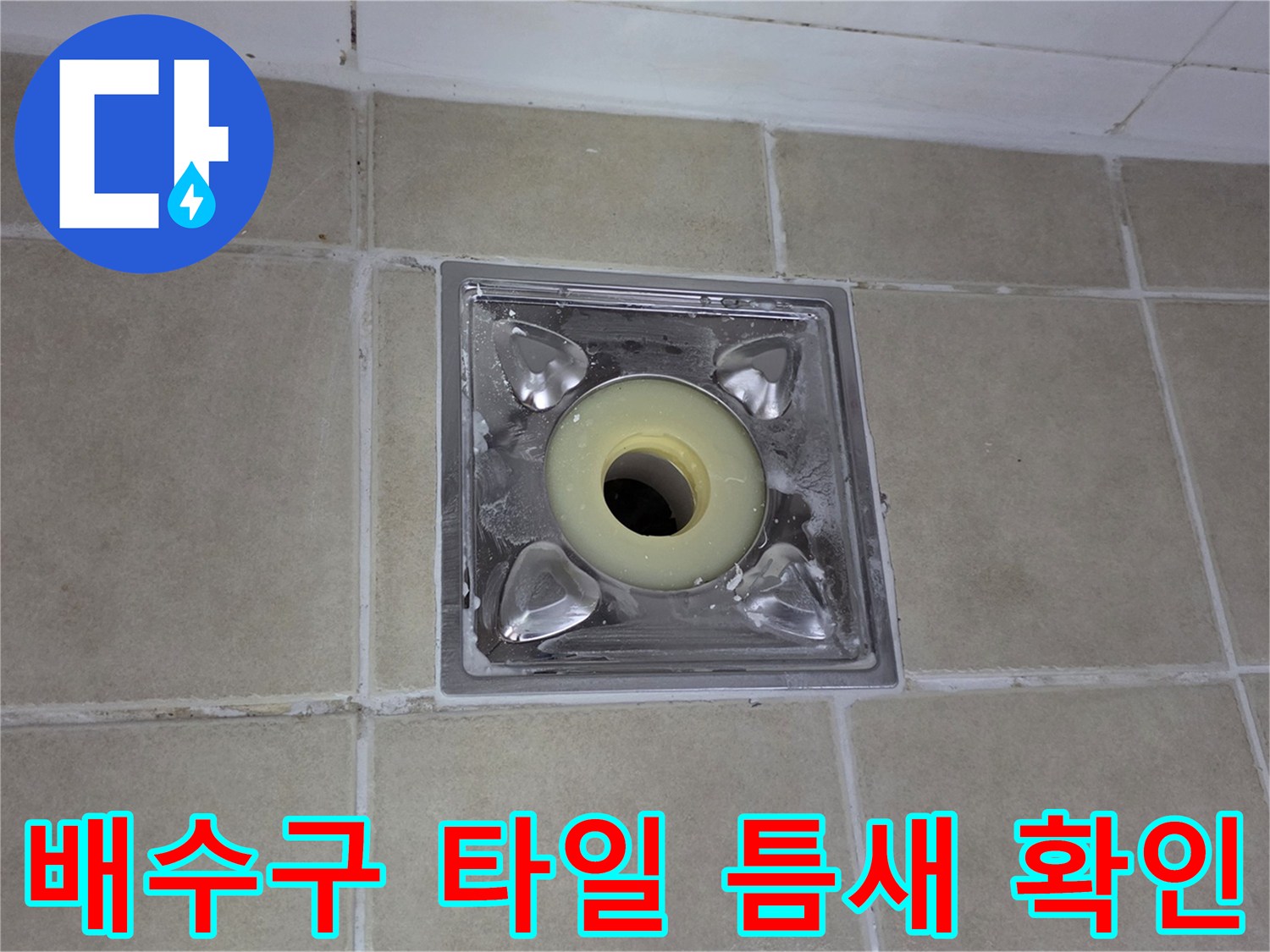 욕실 배수구 주변의 타일 줄눈과 유가 부속 사이의 벌어진 틈새를 촬영한 사진입니다.