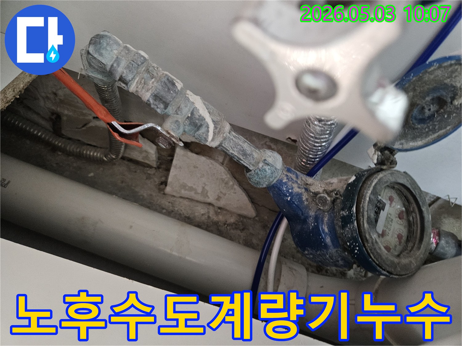 노후된 수도 계량기 아래에서 발견된 누수 현장을-전문가가 면밀히 검토하고 있습니다