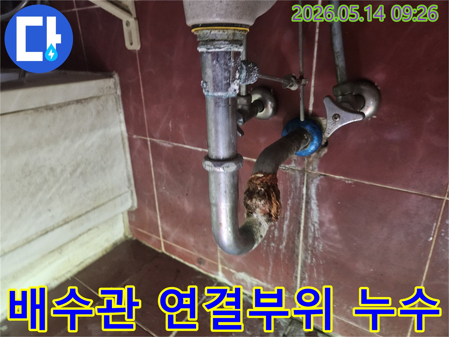 배수관의 연결 부위가 심하게 부식되어-물이 새는 현장을 클로즈업한 사진입니다.