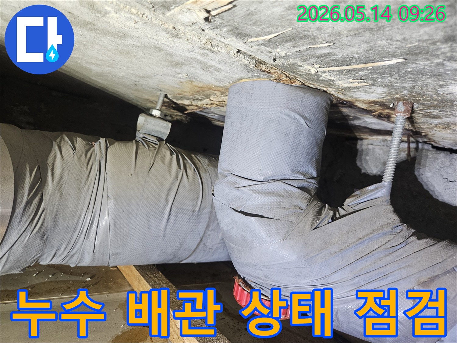 천장 아래 설치된 배관에서 물이 새어-단열재와 주변 목재가 손상된-누수 현장을 보여줍니다