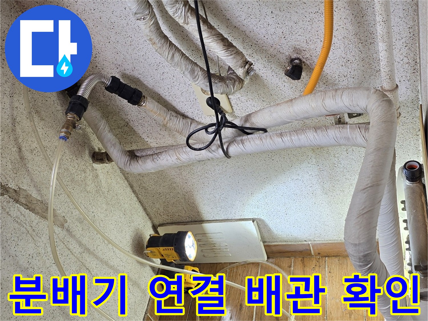 보일러실 하단에 노출된 배관들과 밸브들의 체결 상태를 점검하는 사진입니다.