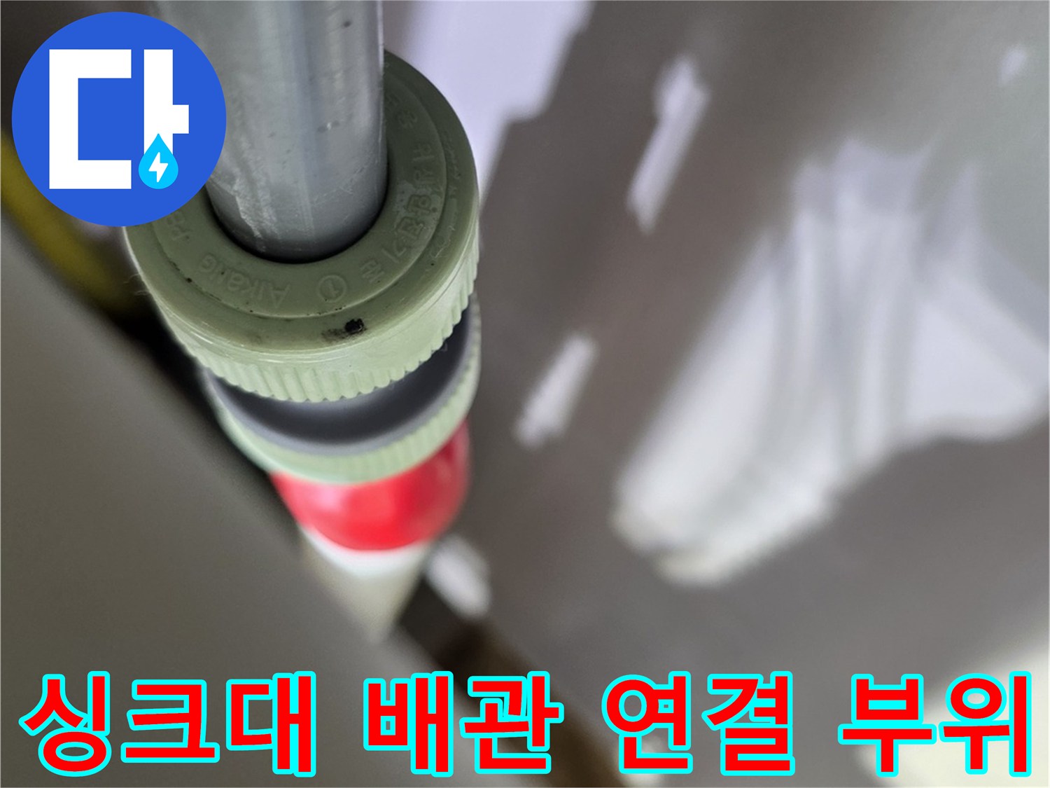 싱크대 하부장 내부의 노후된 배관 연결 부속 상태를 근접 촬영한 사진입니다.