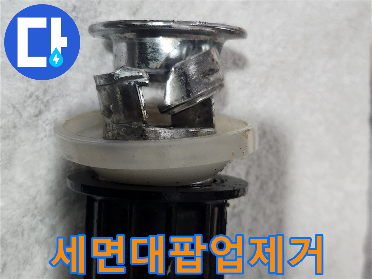 이 이미지는-세면대 배수구의-누수 문제를 일으키던-낡은 팝업 부품을-제거한 상태를 보여줍니다
