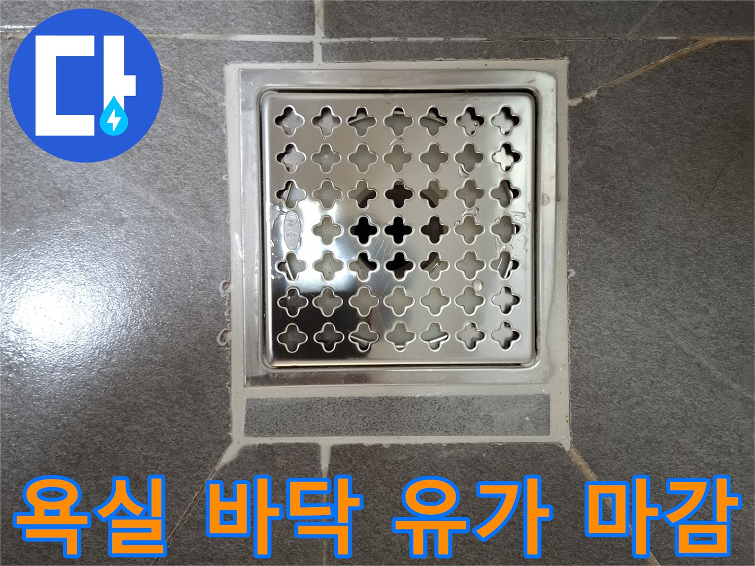 회색 타일과 은색 배수구 덮개가 만나는 지점