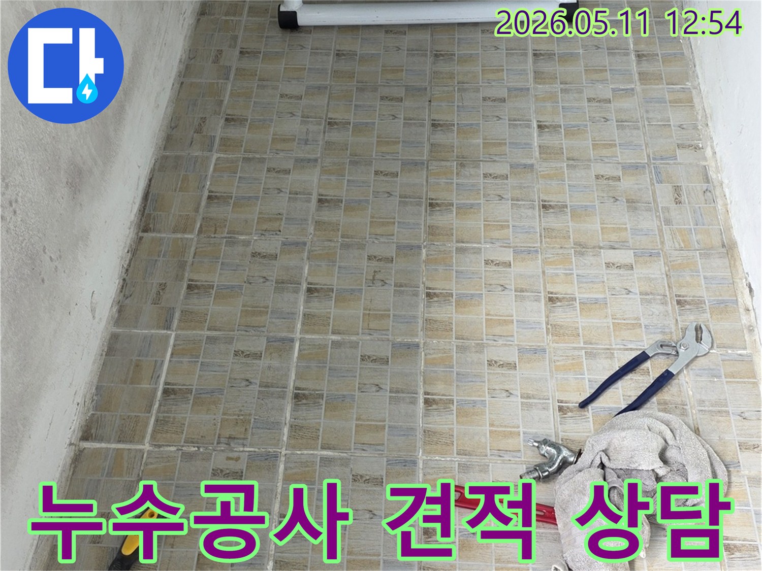 누수 공사 현장에서-타일 벽면과-작업에 필요한 공구들이 놓여있는 모습