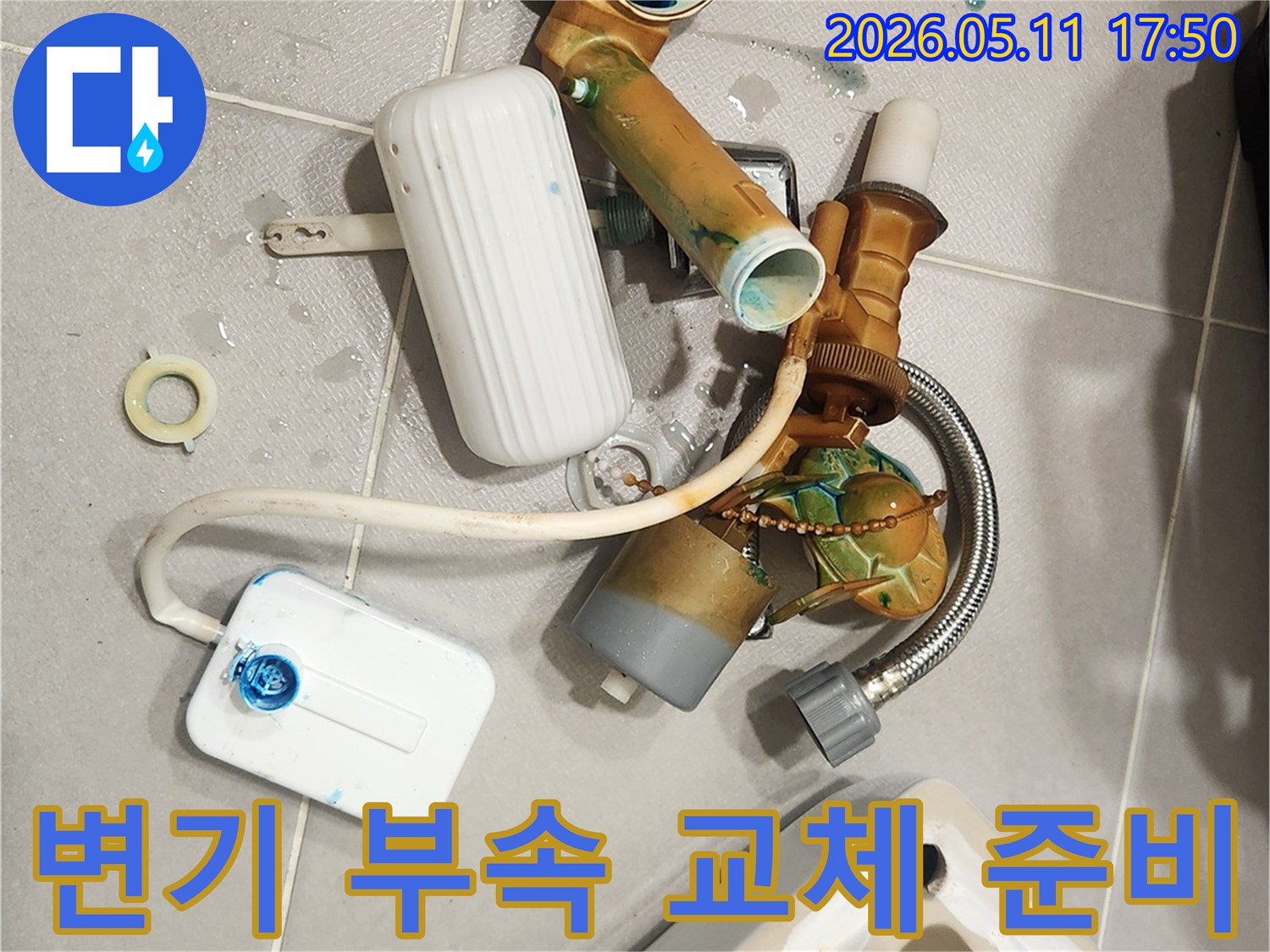 안방 변기에서 발견된 누수 문제로 인해-낡고 부식된 변기 부속들이 해체되어 바닥에 놓여 있습니다-새 부품으로 교체하여 문제를 해결할 준비가 완료되었습니다
