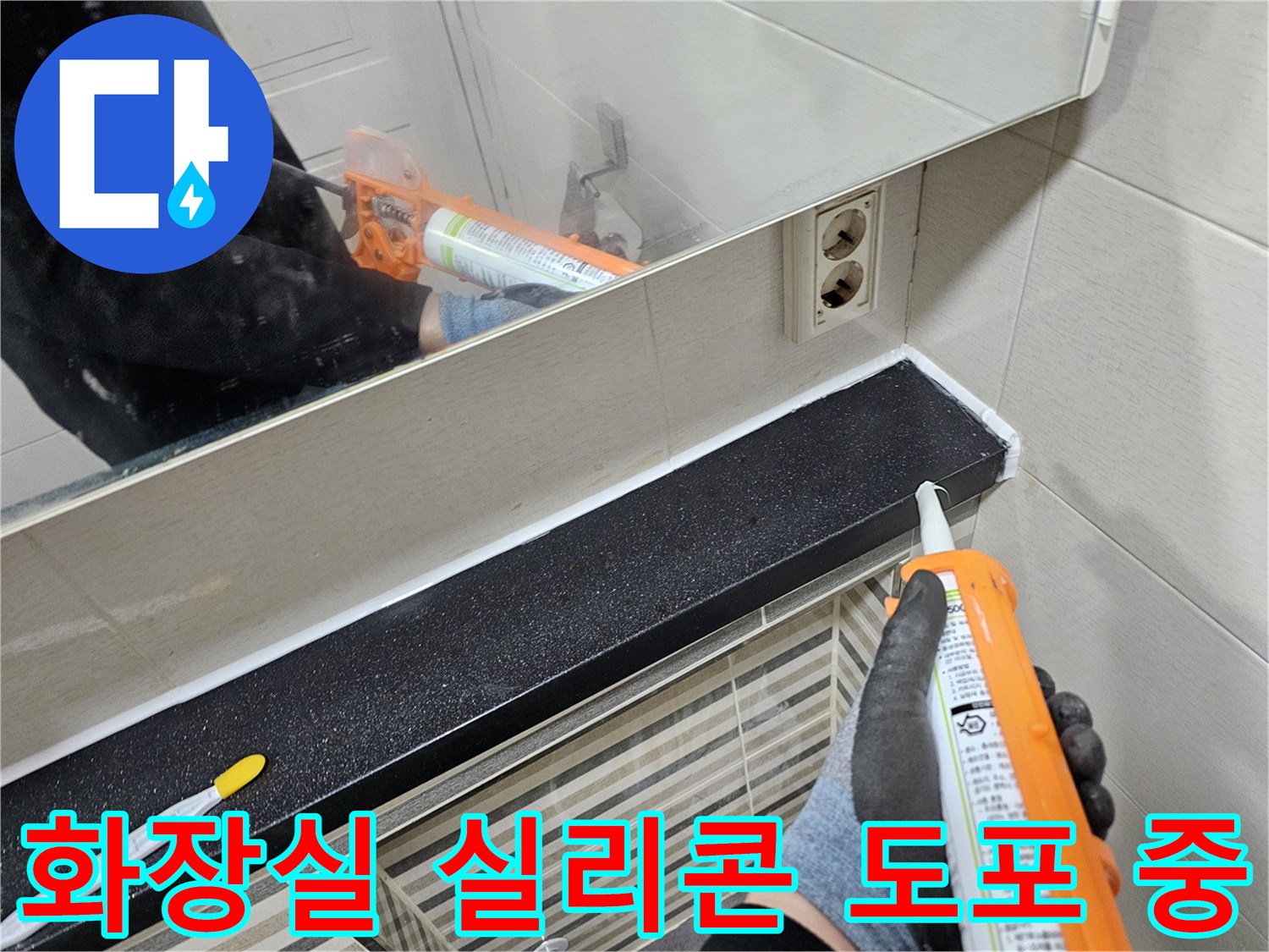검은색 선반 밑 타일 경계에 하얀 실리콘을 채우는 작업