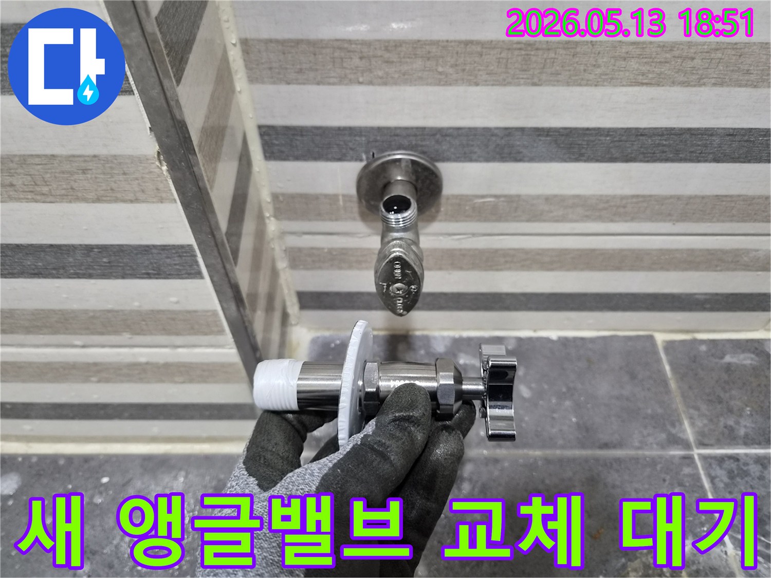 욕실 누수 수리를 위해-엔지니어가 새 앵글밸브를 손에 들고-교체 작업을 준비하고 있습니다.